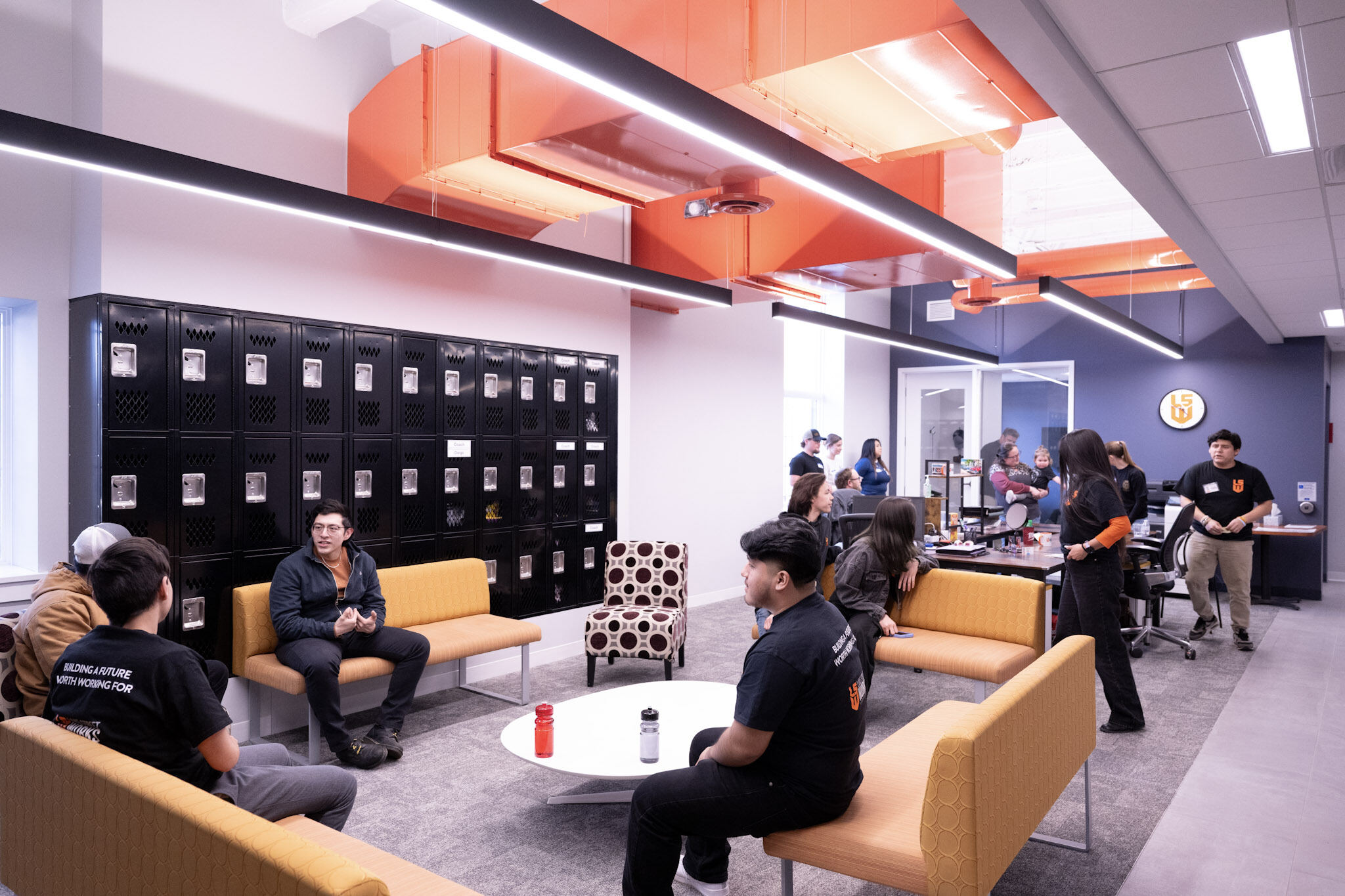 Students and mentors gathered on yellow benches in the Lake Street Works lounge at 3017, beneath the building's signature orange ductwork