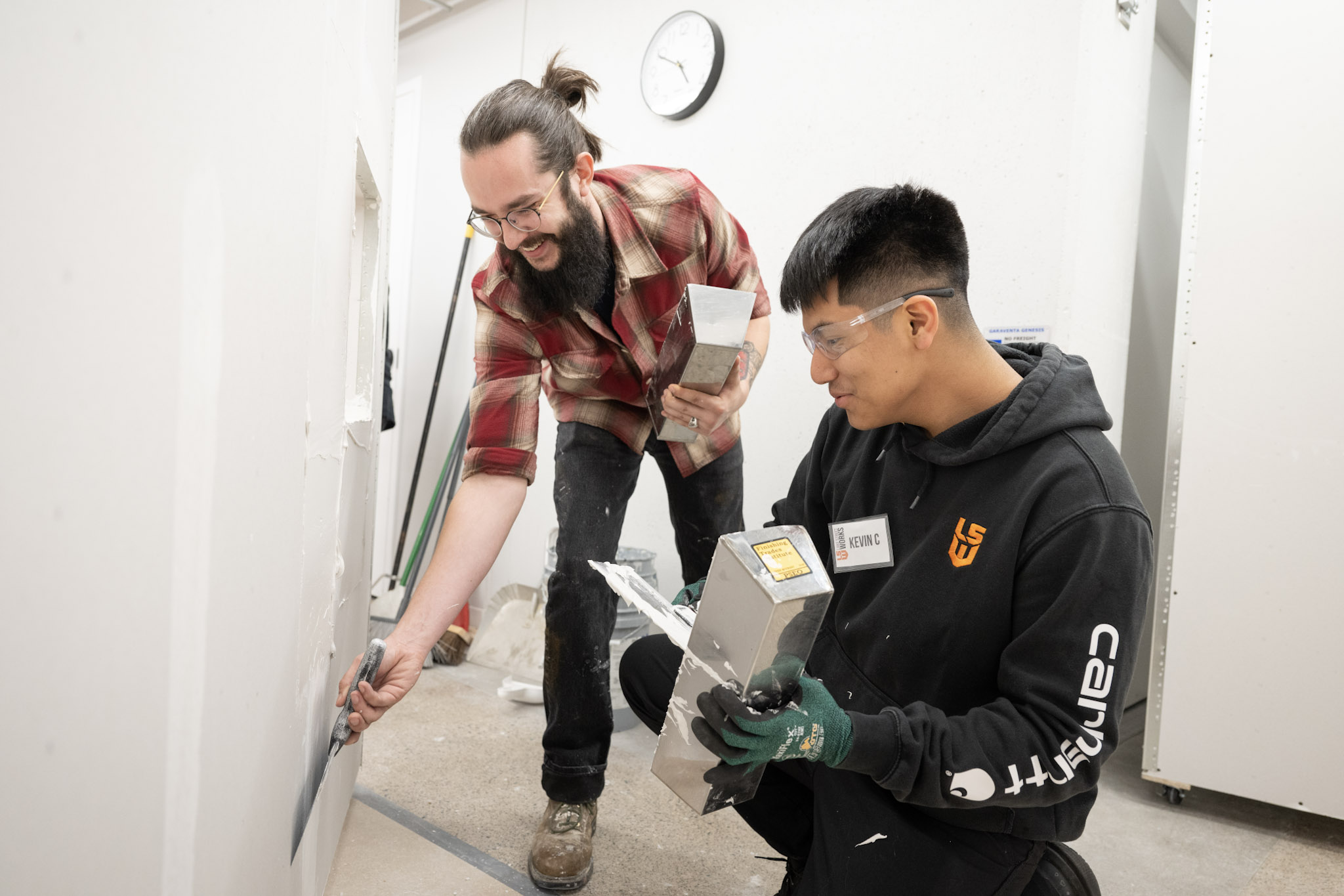 A Lake Street Works student and instructor finishing drywall together in the 3017 training shop
